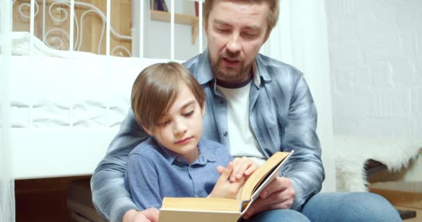 Заботливый Отец Читает Интересную Книгу Своему Маленькому Сыну Дома Родительство — стоковое видео
