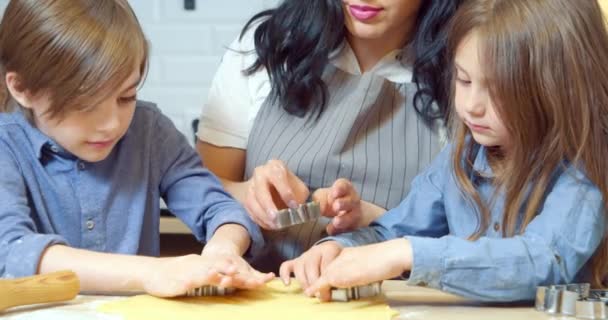靠近一个年轻的母亲和两个孩子 他们在厨房里用饼干切割机从面团中取出饼干 — 图库视频影像