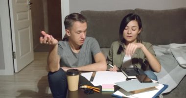 Son teslim tarihine kadar ortak bir projeyi bitiren yorgun genç çift geç saatlere kadar evde yerde oturuyor..