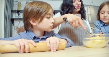 Mutlu aile kurabiye için hamur hazırlıyor. İki tatlı kız ve erkek çocuk mutfakta anneme yardım ediyor..