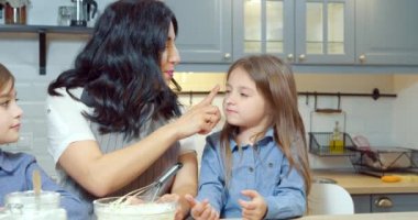 Mutlu aile anne ve iki çocuk mutfakta birlikte ev yapımı kurabiyeler hazırlarken eğleniyorlar.