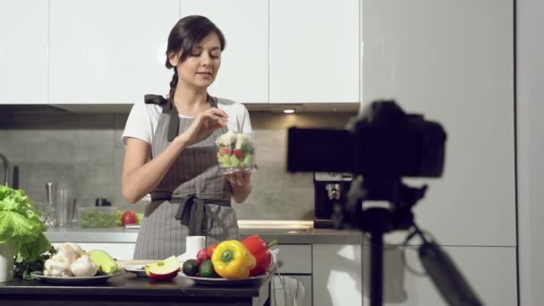 自宅のキッチンでデジタルカメラで健康的な食事についてのビデオを録画する魅力的な若い女性 ブログやソーシャルメディアの概念 — ストック動画