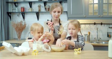 Mutlu bir aile, genç bir anne ve iki küçük kız mutfakta kurabiye için para kazanıyorlar.