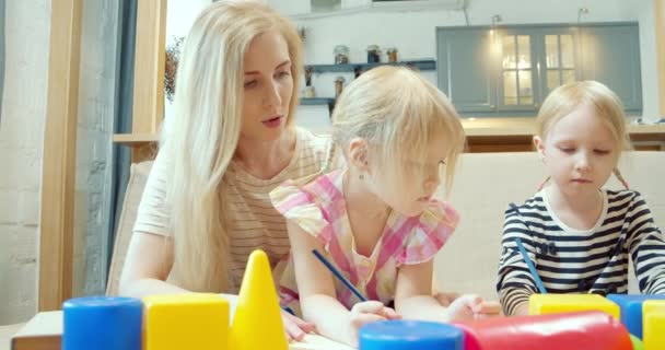 年轻的母亲和两个小女孩在家里用彩色铅笔在纸上画画 幼儿教育和创造力概念 — 图库视频影像