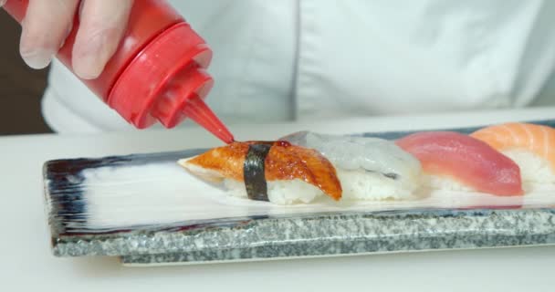 皿の上で新鮮な刺身を閉じます 男性の手寿司は 料理に具材のソースとゴマを敷設料理します 寿司を作る過程 — ストック動画