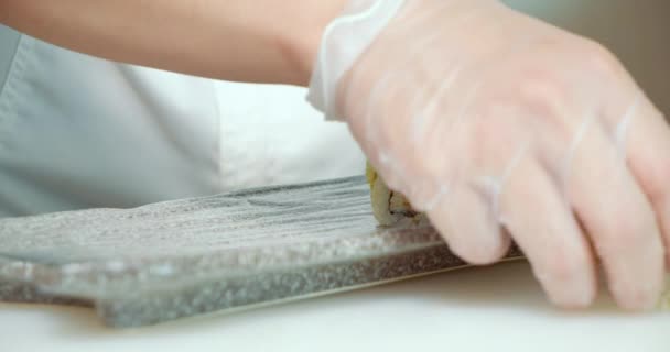皿の上にアボカドとマグロと寿司ロールを敷く手袋で料理人の男性の手を閉じます — ストック動画