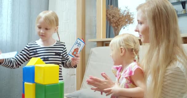可爱的女孩向妹妹和妈妈展示带有信件和照片的卡片 在游戏中学习字母 学前教育 — 图库视频影像
