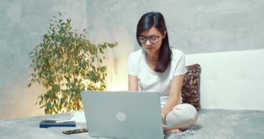 Laptop klavyesinde yazan genç bir kadın. Sosyal ağlarda yazı yazan serbest çalışan kadın ya da öğrenci evdeki yatakta oturuyor..