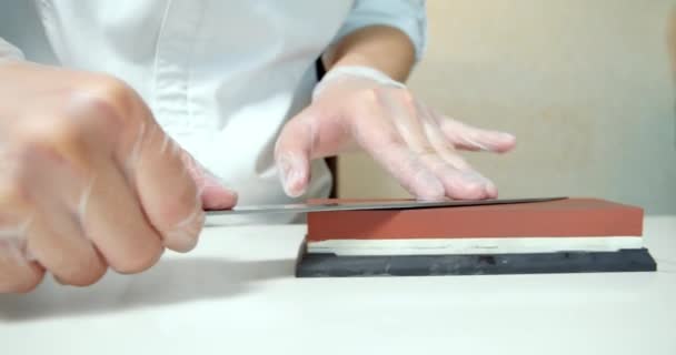シェフの手はスローモーションでナイフを研ぎます キッチンレストランで食品を調理するための専門的なツールを準備人の手を閉じます — ストック動画