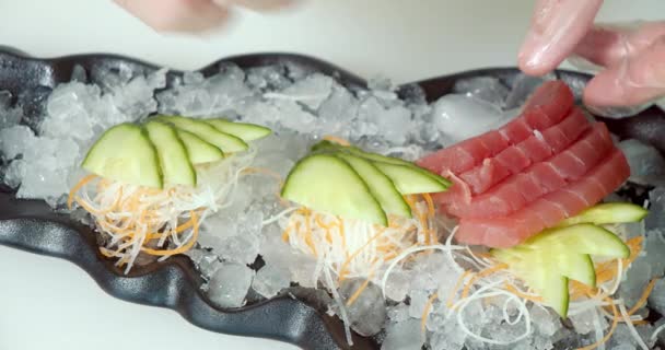 一个戴着手套的厨师的亲密的男性手 把新鲜的鱼和蔬菜放在盘子里的冰底上 — 图库视频影像