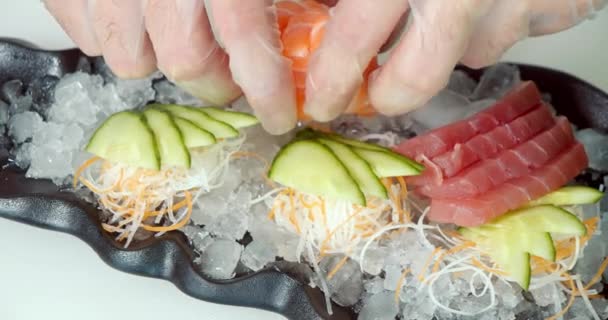 氷の基板上に新鮮な魚や野菜の刺身を敷く手袋にコックの男性の手の閉じる — ストック動画