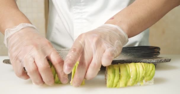 Großaufnahme Männlicher Kochhände Handschuhen Die Köstliche Sushi Rollen Mit Avocado — Stockvideo
