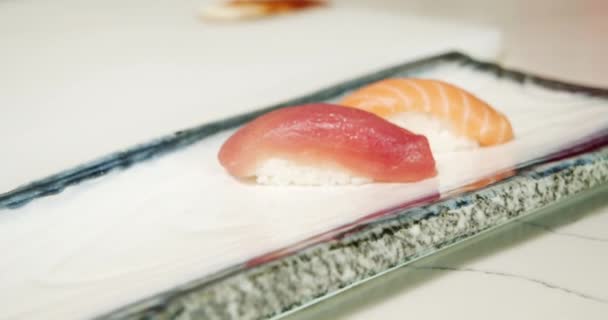 エビなどのおいしい刺身が皿の上に閉じ込められています 寿司巻きを出す料理人の手 — ストック動画