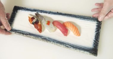 Bir tabakta pilav, balık ve karidesli lezzetli sashimi. Şefin elleri suşi servis ediyor..
