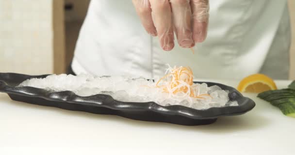 男厨师的特写镜头手拿着手套 用冰块在盘子里放上乳酪和胡萝卜沙拉 做生鱼片 — 图库视频影像