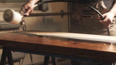 Erkek bir marangozun, ahşap bir masanın üstüne sıkıştırılmış hava kullanarak vernik ya da astar püskürten ellerine yakın plan. Mobilya üretimi.
