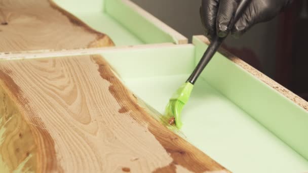 手握手套的工匠用刷子在木制桌面上涂清漆或底漆的特写镜头 — 图库视频影像