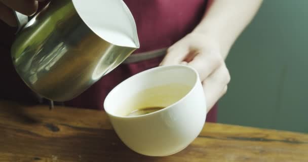 完成了咖啡的制作过程 巴里斯塔男性的手把奶油牛奶倒入一杯加黑咖啡的杯子里 — 图库视频影像