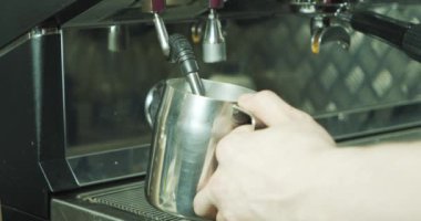 Kahve yapma sürecini kapat. Kahve dükkanında kapuçino için süt sallayan profesyonel bir barista.