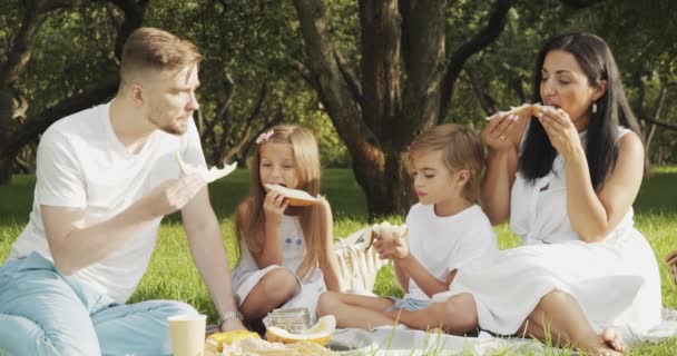 Mutlu Çocuklu Bir Aile Yeşil Bahçede Piknik Yaparken Çimenlerde Dinleniyor — Stok video