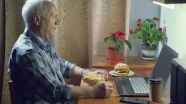 Yaşlı bir adam duygusal olarak en sevdiği takımı destekliyor. Evde dizüstü bilgisayardan maç seyrediyor..