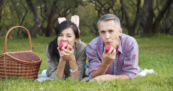 Portrait Happy Couple Eating Apples Looking Camera Lying Grass Park — Stock Video