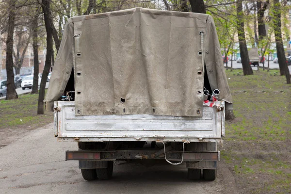 Back of old car with torn awning and instruments, staying outdoor on street