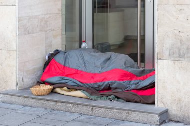 MUNICH, GERMANY - JANUARY 7, 2018: Homeless man sleeps on the floor clipart