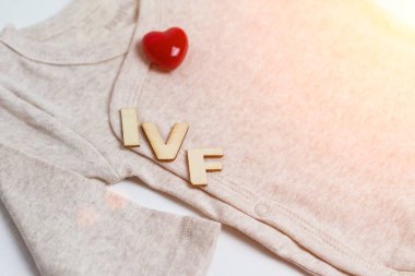 Baby clothes with test-tube and heart. Concept - IVF, in vitro fertilization. Waiting for baby, pregnant. clipart