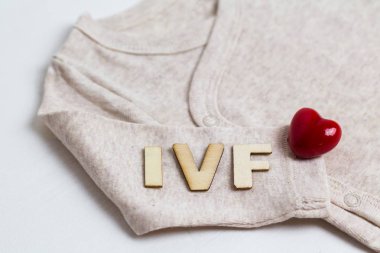 Baby clothes with test-tube and heart. Concept - IVF, in vitro fertilization. Waiting for baby, pregnant. clipart
