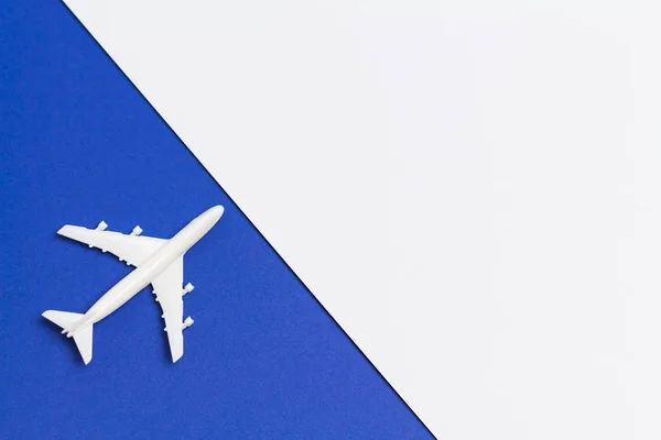 Küçük beyaz uçak, beyaz ve mavi arka plan rengi kağıtlara çapraz olarak düzenlenmiş.