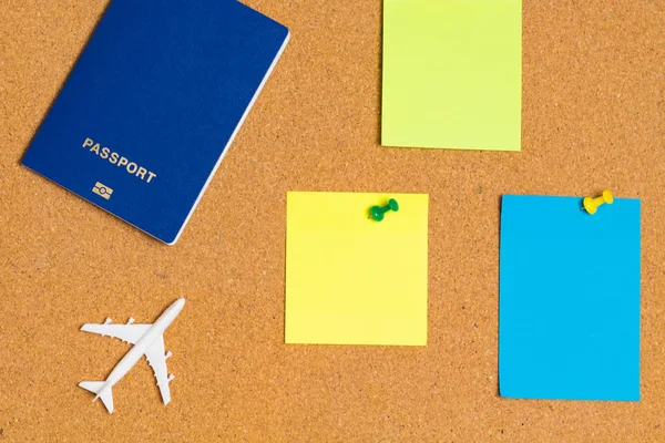 Beyaz mavi pasaport ve mantar pano mavi, turuncu, sarı kağıt Not iğnesi ile yolcu uçağı modeli. Metin mesajı veya tasarım Web sitesi eklemek için boş Not. etiket dikkat, kopya alanı.