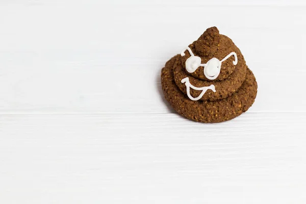 Funny poop emoji chocolate cookie with white decor and glasses. Cute food dessert in right corner. Free place for text. Copyspace.