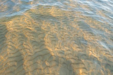 Yumuşak kum plajındaki su dalgası. Suyun altında kum dalgaları