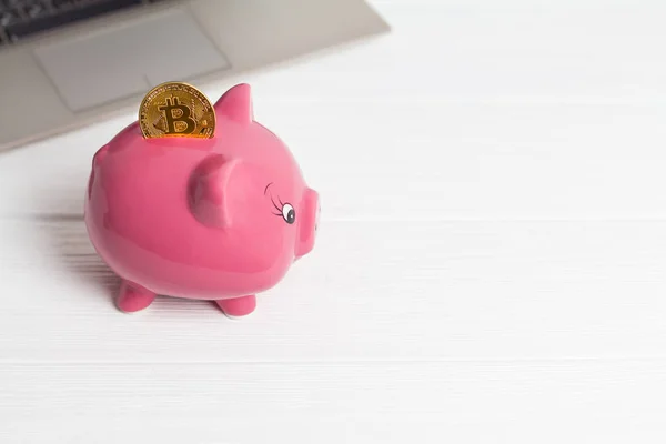 Golden bitcoin on the piggy bank money box with a computer on background. Cryptocurrency investment concept. Virtual money. Web banking, network payment.