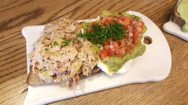 Avokado tost domates ve beyaz tahta, havai görünümü ton balığı. Mobil fotoğrafçılık.
