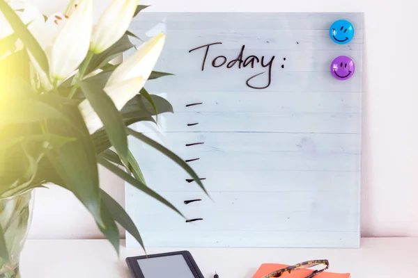 Beyaz Resepsiyon çalışma alanıyla teklif bugün Danışma, Beyaz lilyum, yeşil yaprakları ve ofis malzemeleri. Defter, makas, beyaz arka plan üzerinde gözlük.