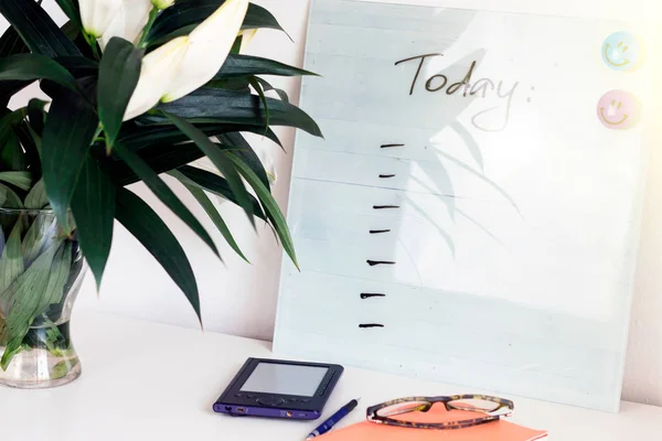 Beyaz Resepsiyon çalışma alanıyla teklif bugün Danışma, Beyaz lilyum, yeşil yaprakları ve ofis malzemeleri. Defter, makas, beyaz arka plan üzerinde gözlük.