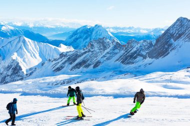 Zugspitze, Almanya - 29 Aralık 2018: Zugspitze dağındaki kayak alanında birçok kişi. Kar kayaklarında renkli kayak takımları giyen insanlar. Alplerin güzel manzarası