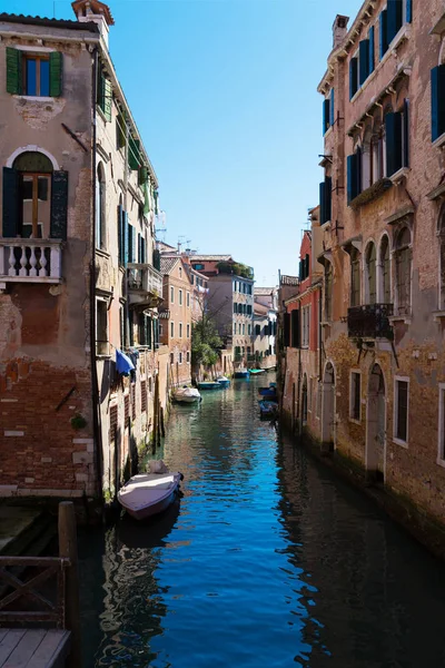 Canal estreito velho com barcos estacionados, Veneza, Itália. Rua inundada tradicional ou beco de Veneza. Vista vertical . — Fotografia de Stock