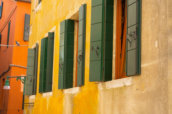 Italian building exterior. Colorful walls, cute terraces and colorful green window shutters. Italian style
