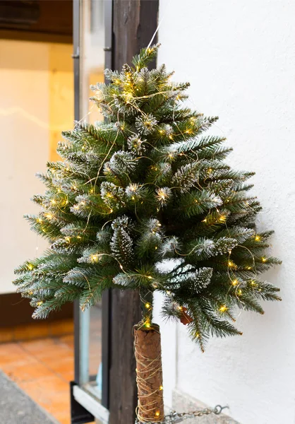 Pequeño árbol de Navidad decorado cerca de la entrada de la tienda. Vertical —  Fotos de Stock