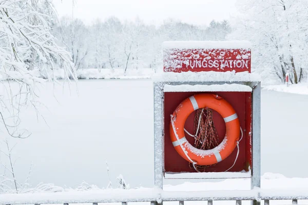 Almanya 'daki kış gölünde güvenlik ekipmanları. Rıhtımdaki parlak kırmızı can simidi