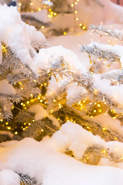 Bokeh amarillo de la luz decorativa en el árbol de Navidad y la nieve en el fondo —  Fotos de Stock