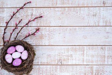 Paskalya arka plan beyaz ahşap rustik masa - kopya alanı üzerinden bir yuvada renkli yumurta ile