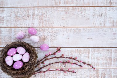 Paskalya arka plan beyaz ahşap rustik masa - kopya alanı üzerinden bir yuvada renkli yumurta ile