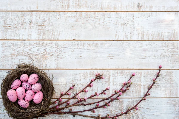 Paskalya arka plan beyaz ahşap rustik masa - kopya alanı üzerinden bir yuvada renkli yumurta ile