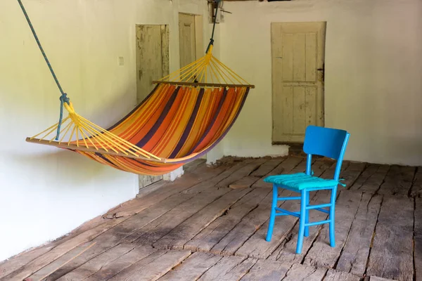 Pórtico de madeira de uma antiga casa de campo vintage com mesas, cadeiras e rede - um lugar para comer e relaxar — Fotografia de Stock