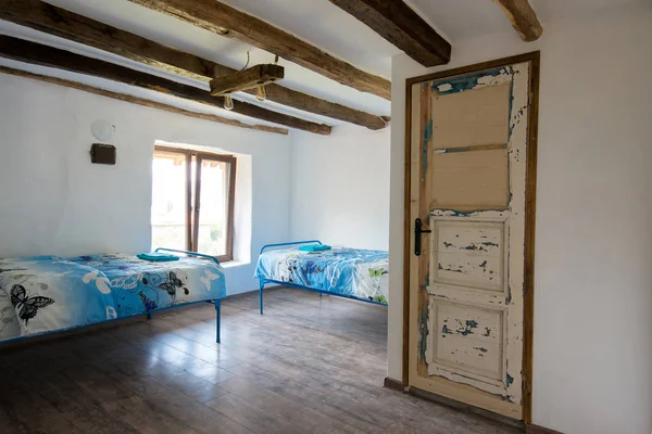 Rumah tua yang indah - interior kamar tidur dengan langit-langit balok kayu dan selimut biru dan seprai — Stok Foto