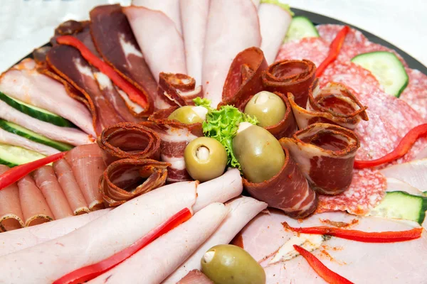 Catering mat för evenemanget - olika typer av delikatesser av kött och ost arrangeras i en platta över ljus bakgrund - selektivt fokus — Stockfoto